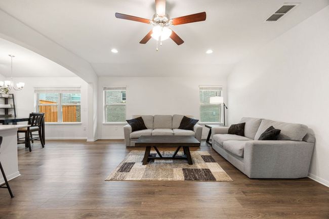 Living room with vaulted ceiling, healthy amount of natural light, dark wood finished floors, a chandelier, and ceiling fan | Image 6