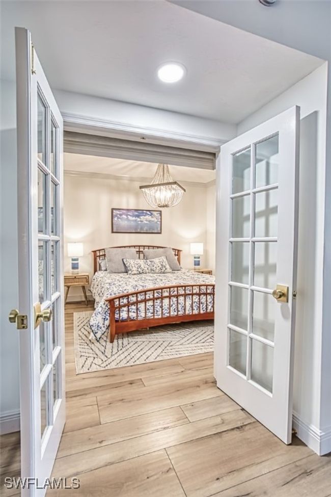 Bedroom featuring french doors, wood finished floors, a chandelier, and recessed lighting | Image 40