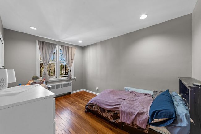 Bedroom featuring wood-type flooring, radiator heating unit, baseboards, and recessed lighting | Image 22