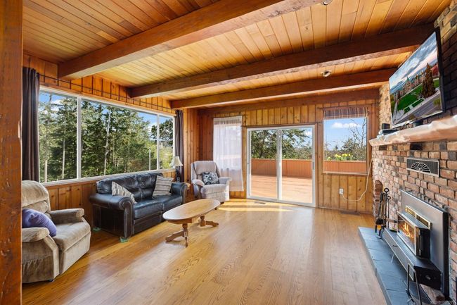 Living room with wooden walls, wood finished floors, wood ceiling with exposed beams, and healthy amount of natural light | Image 15