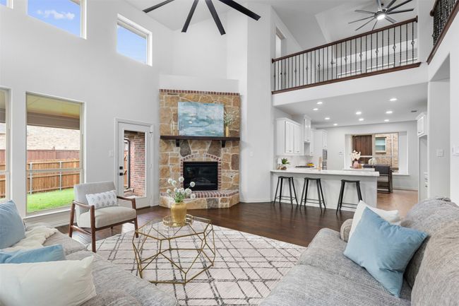 Living room featuring a towering ceiling, a ceiling fan, wood finished floors, and a healthy amount of sunlight | Image 14