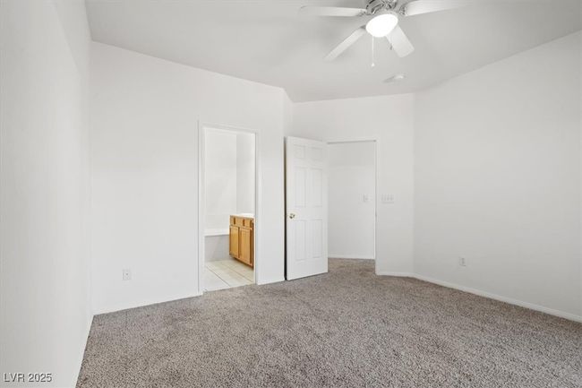 Unfurnished bedroom featuring light colored carpet, ensuite bath, baseboards, and ceiling fan | Image 14