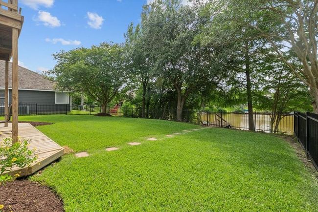Welcome to your spacious backyard with lush green grass, a balcony and patio area, surrounded by trees and perfect for outdoor gatherings and relaxing. | Image 37