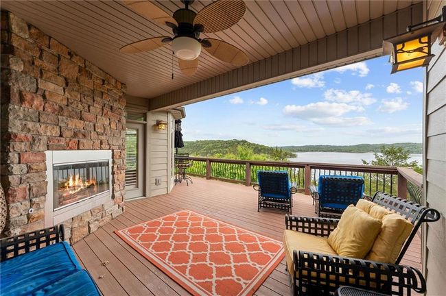 Wooden deck with a ceiling fan, a water view, and an outdoor stone fireplace | Image 4