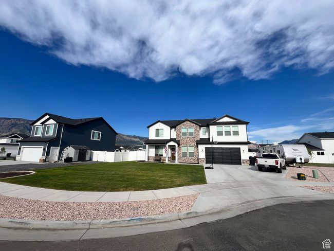 View of front of home featuring an attached garage, stone siding, concrete driveway, and a residential view | Image 28