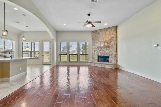 Unfurnished living room with light wood-type flooring, a ceiling fan, a stone fireplace, arched walkways, and recessed lighting | Image 13
