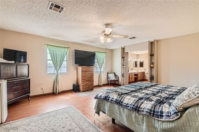 Bedroom featuring ensuite bathroom, wood finished floors, visible vents, and baseboards | Image 18