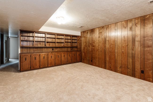 Finished basement featuring carpet floors, wooden walls, and a textured ceiling | Image 21