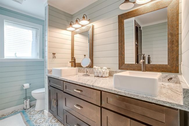 Bathroom with wooden walls, double vanity, toilet, and a sink | Image 29