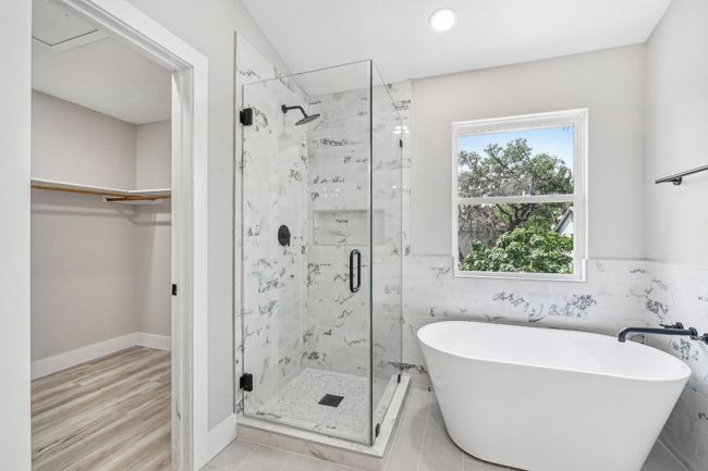 Bathroom featuring a freestanding tub, a stall shower, a spacious closet, tile walls, and recessed lighting | Image 6