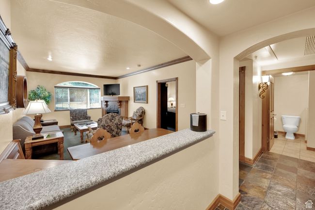 Interior space with stone finish flooring, a fireplace, baseboards, arched walkways, and ornamental molding | Image 31