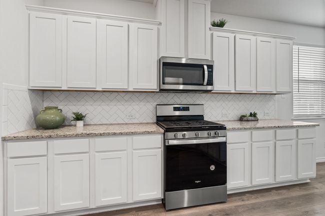 Kitchen with appliances with stainless steel finishes, white cabinets, decorative backsplash, and wood finished floors | Image 9