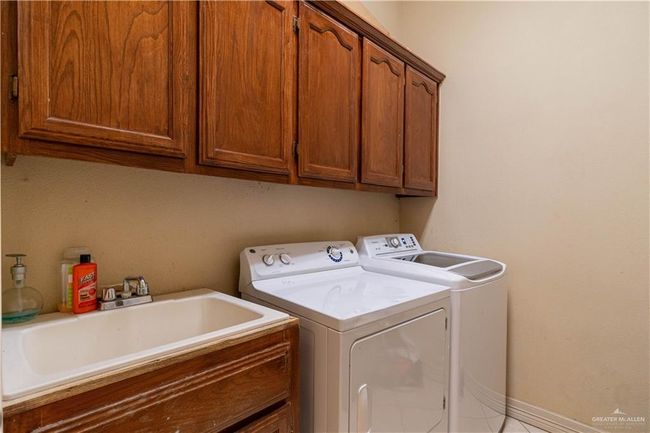 Laundry room with cabinets, sink, and washing machine and clothes dryer | Image 18