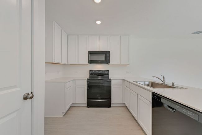 Kitchen featuring black appliances, light countertops, white cabinets, and recessed lighting | Image 13