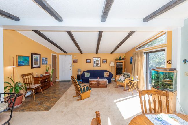 Living room with lofted ceiling with beams, carpet floors, and a textured ceiling | Image 9