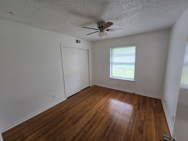 Unfurnished bedroom featuring dark wood-style floors, a textured ceiling, a closet, and a ceiling fan | Image 5