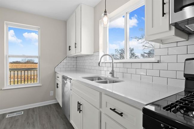Kitchen with appliances with stainless steel finishes, a sink, dark wood finished floors, light countertops, and white cabinets | Image 7