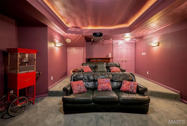 Carpeted home theater room featuring a raised ceiling and ornamental molding | Image 46