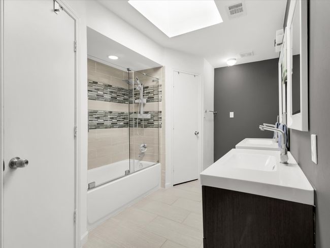 Full bathroom featuring shower / washtub combination, double vanity, a skylight, and tile patterned floors | Image 19
