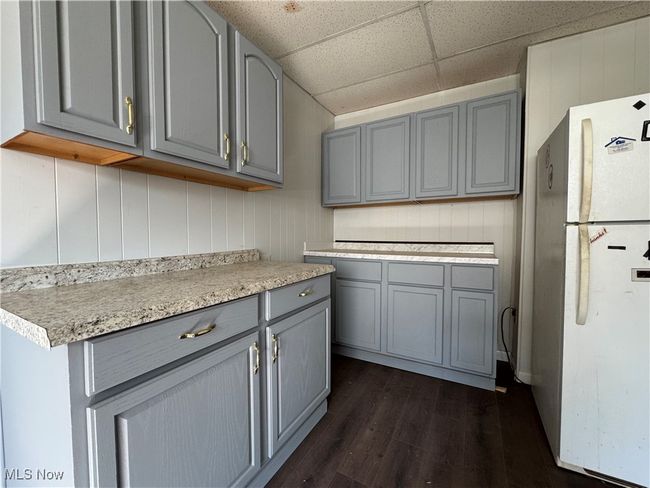 Kitchen featuring dark wood-style floors, a paneled ceiling, light countertops, gray cabinetry, and freestanding refrigerator | Image 18
