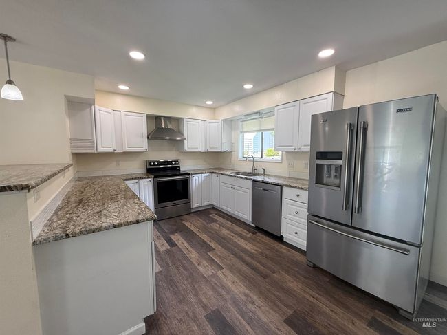 Kitchen featuring stainless steel appliances, wall chimney exhaust hood, dark wood-style floors, white cabinetry, and stone counters | Image 15