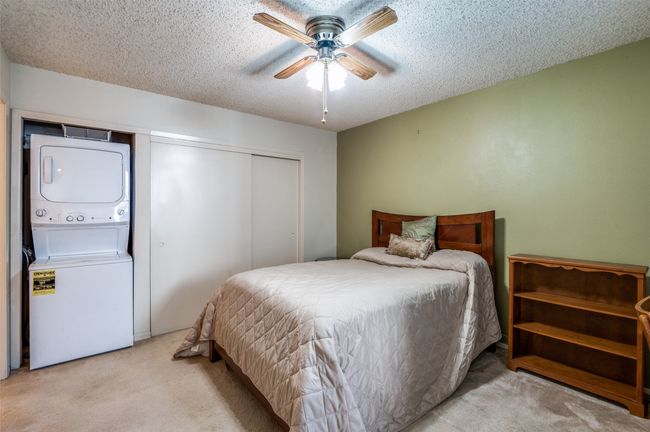 Carpeted bedroom featuring estacked washer and dryer, a textured ceiling, a closet, and ceiling fan | Image 16