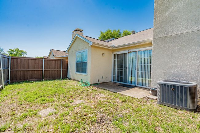 Rear view of house featuring a lawn, a chimney, a fenced backyard, cooling unit, and stucco siding | Image 10