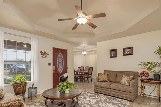 Living room featuring a raised ceiling, a ceiling fan, and light wood finished floors | Image 5