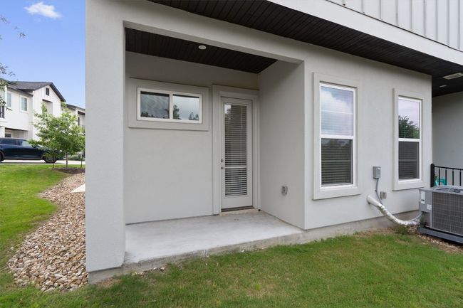 View of exterior entry with stucco siding, a lawn, and a patio | Image 14