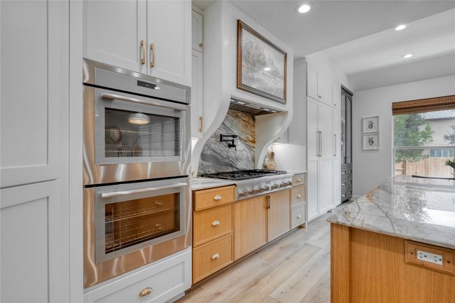 Kitchen featuring stainless steel appliances, backsplash, light wood finished floors, recessed lighting, and light stone countertops | Image 20