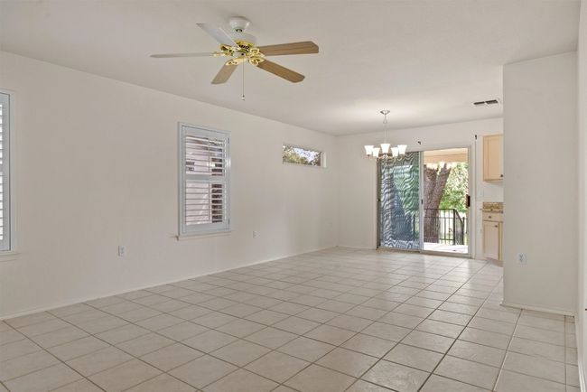 Living/Dining with a chandelier, light tile patterned floors, and a ceiling fan | Image 8
