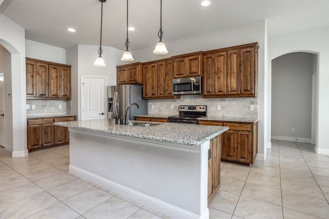 Kitchen with appliances with stainless steel finishes, arched walkways, light tile patterned floors, decorative backsplash, and recessed lighting | Image 14