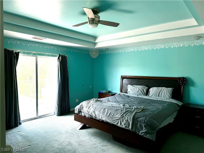 Master Bedroom Suite with a raised coffered ceiling, ceiling fan, and large private balcony | Image 13