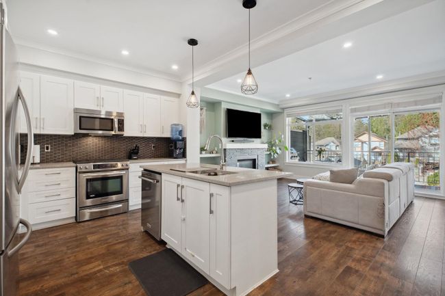 Kitchen with open floor plan, dark wood-type flooring, appliances with stainless steel finishes, and a sink | Image 10