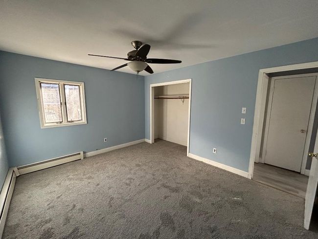 Unfurnished bedroom with baseboard heating, ceiling fan, and carpet flooring | Image 16