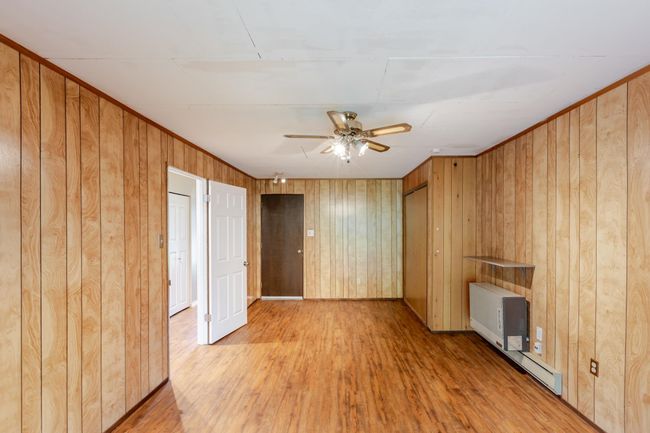Recreation room with a ceiling fan, crown molding, wood walls, and wood finished floors | Image 30