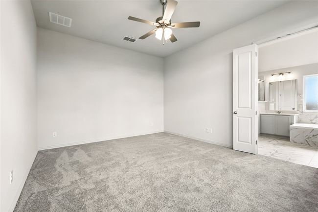 Unfurnished bedroom with light colored carpet, ensuite bathroom, and ceiling fan | Image 21