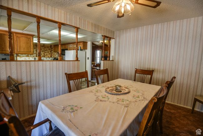 Dining room with wallpapered walls, a ceiling fan, dark colored carpet, and a textured ceiling | Image 30
