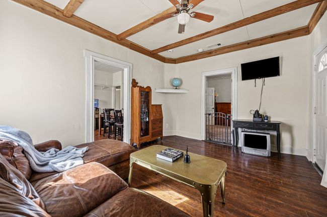 Living room with wood-type flooring, baseboards, and beamed ceiling | Image 7