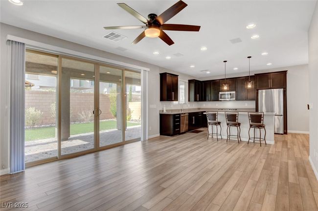 Kitchen featuring stainless steel appliances, a breakfast bar, light countertops, baseboards, and dark brown cabinets | Image 22