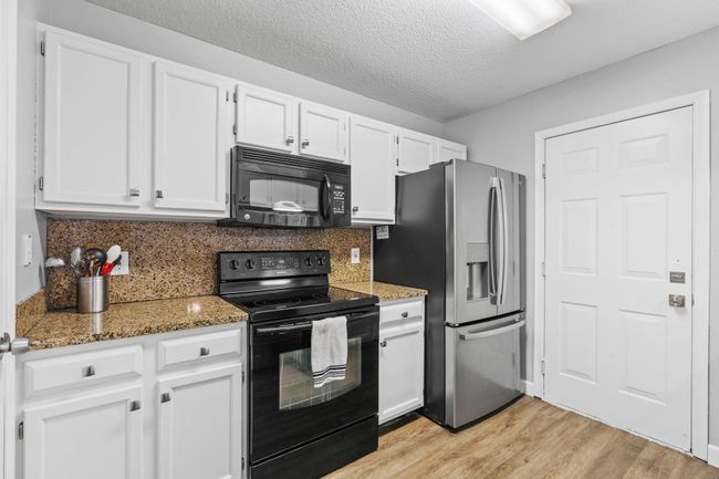 Well-appointed kitchen with granite countertops, stainless steel fridge, and ample cabinet space. | Image 9