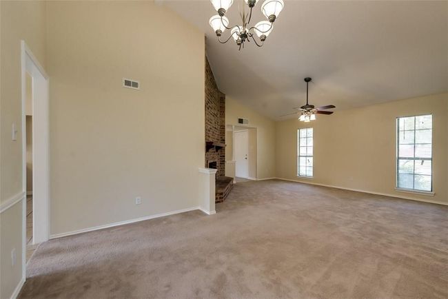 Unfurnished living room featuring high vaulted ceiling, a chandelier, carpet, ceiling fan, and baseboards | Image 5