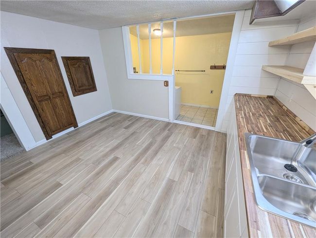 Laundry area with light wood finished floors, a sink, and a textured ceiling | Image 24