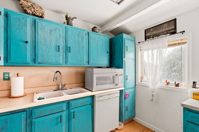 Separate apartment above garage - Kitchen with light countertops, a sink, blue cabinetry, and white appliances | Image 70