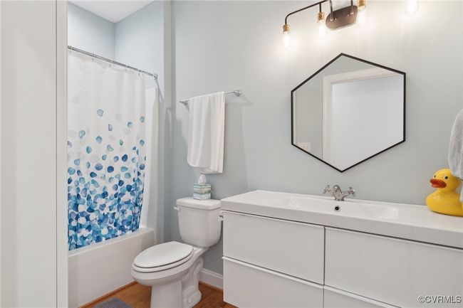 Bathroom featuring shower / tub combo with curtain, toilet, wood finished floors, and vanity | Image 32