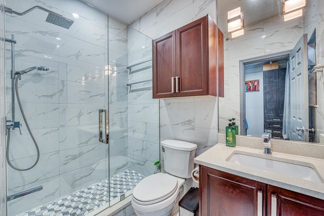 Bathroom with a marble finish shower, vanity, and tile walls | Image 18