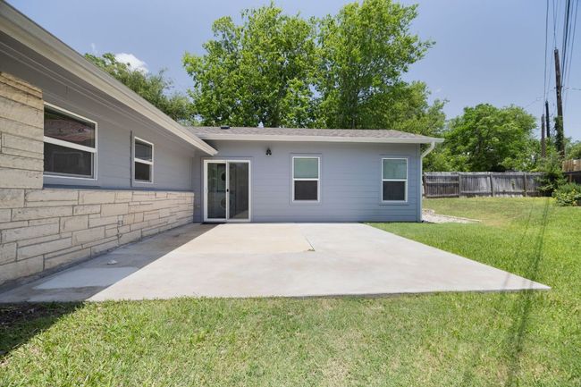 Back of house with a fenced backyard, a patio area, stone siding, and roof with shingles | Image 34