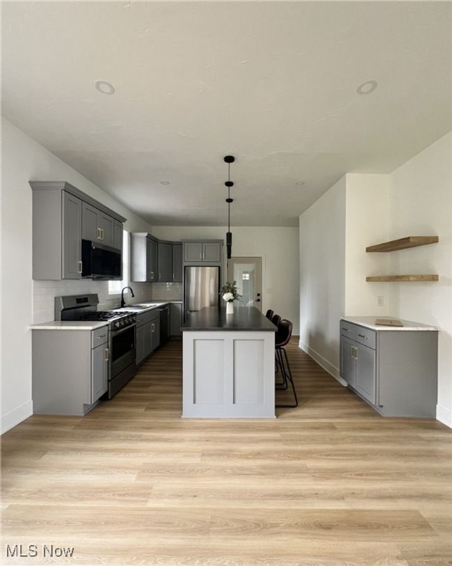Kitchen with light wood-style floors, appliances with stainless steel finishes, and gray cabinetry | Image 7