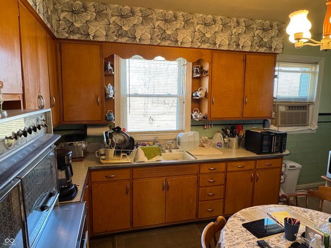 kitchen with brown cabinets, wallpapered walls, a sink, open shelves, and an inviting chandelier | Image 16