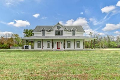 Farmhouse inspired home featuring a porch and a front yard | Image 1